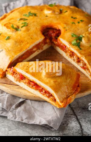 Empanada Gallega grande torta salata a due croste della Galizia ripiena di carne, peperoni rossi, pomodoro e un sacco di cipolla in primo piano sul tavolo. Foto Stock