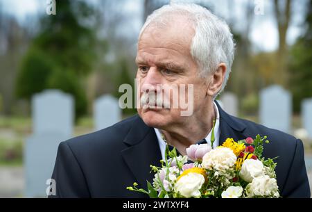 Vecchio triste con fiori che piangono al cimitero. Foto Stock