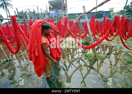 I lavoratori del Bangladesh raccolgono i tessuti dopo averli asciugati sotto il sole in una fabbrica di tintura a Narayanganj, vicino a Dacca, Bangladesh, il 20 marzo 2024. Foto di Habibur Rahman/ABACAPRESS.COM Foto Stock