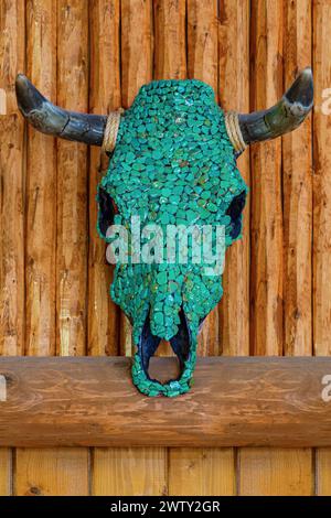 Scultura decorata del cranio di mucca con pietre preziose semi-preziose del turchese su sfondo in legno. Nativo indiano Navajo, opera d'arte artigianale teschio di toro Turchese. Teschio di mucca decorato Foto Stock