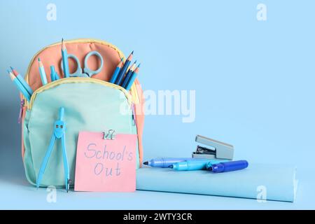 Carta con testo SCOLASTICO FUORI, zaino e cancelleria diversa su sfondo blu Foto Stock