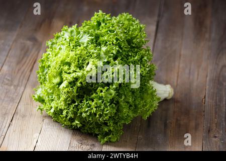 Un grosso mazzo di foglie di lattuga verde fresche su uno sfondo di legno. Cibo sano, fonte di minerali e vitamine. Foto Stock