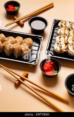 Set di panini di sushi con salmone, formaggio cremoso, semi di sesamo in una confezione di plastica, bastoncini cinesi, salsa di soia su sfondo leggero. Consegna di sushi Foto Stock