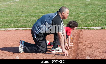 Padre e bambino latinoamericano che giocano per correre su una pista Foto Stock