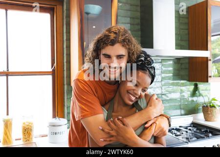 Una coppia varia condivide un caldo abbraccio in cucina a casa Foto Stock