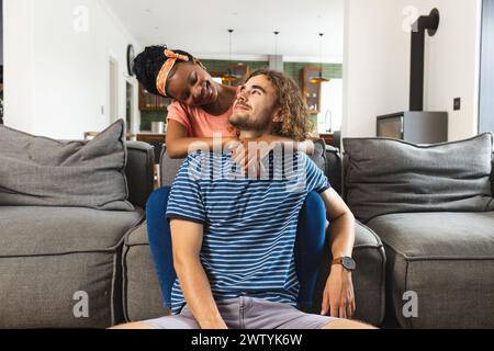 Una coppia diversificata condivide un momento di tenerezza a casa Foto Stock