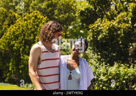 Una coppia variegata gode di una giornata di sole all'aperto a casa nel giardino Foto Stock