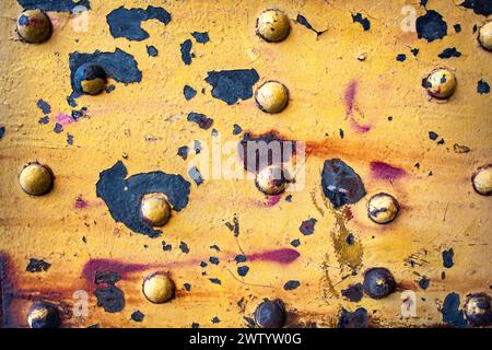 Vecchia superficie in metallo arrugginito con bulloni e vernice gialla spellata Foto Stock