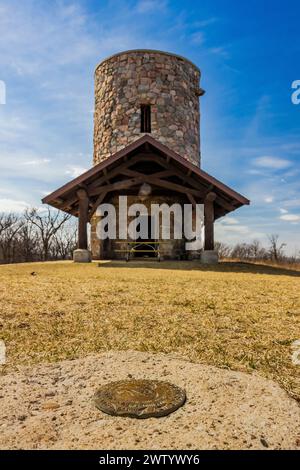 L'indicatore USGS Survery si trova di fronte alla torre di osservazione in pietra costruita dal CCC nel Pilot Knob State Park, Iowa, USA Foto Stock