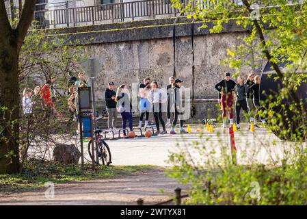 Monaco, Germania-marzo 3,2024,:Un gruppo di persone si prende una pausa durante una sessione sportiva all'aperto. Foto Stock