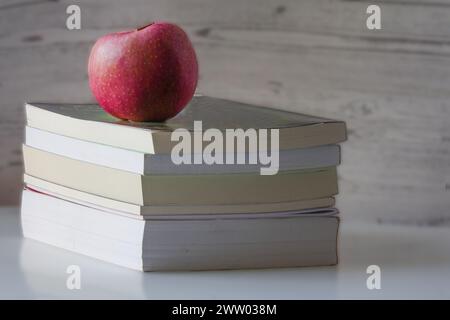 Mela rossa in cima a una pila di libri Foto Stock