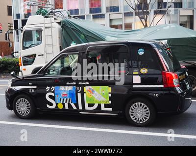 TOKYO, GIAPPONE - 19 marzo 2024: Un taxi nel traffico nella zona di Omotesando a Tokyo. Sul lato sono presenti delle etichette di sicurezza stradale. Foto Stock