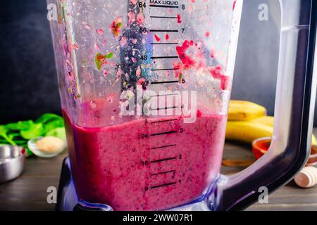 Vista laterale di un frullato di frutti di bosco misti di arancia sangue nel frullatore: Frullato morbido con arance rosse, bacche miste, banana, spinaci piccoli e molto altro ancora Foto Stock