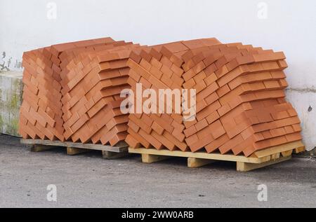 Una pila di mattoni ordinatamente disposti su un pallet di legno in un cantiere edile. Foto Stock