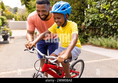 Il padre afroamericano insegna a suo figlio di andare in bicicletta Foto Stock