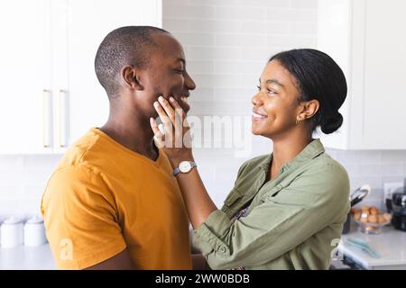 La coppia afroamericana condivide un momento tenero in cucina a casa Foto Stock