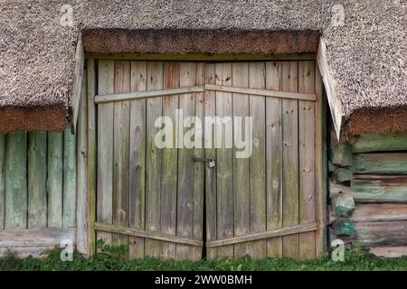 Porte doppie con serratura in un antico edificio con tetto in paglia. Foto Stock