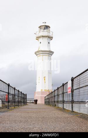 Newhaven, Scozia, Regno Unito - marzo 2024: Il faro del porto di Newhaven si trova alla fine della frangiflutti con recinzioni metalliche su ciascun lato. Foto Stock