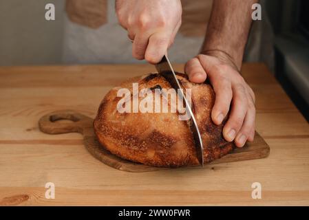 l'uomo affetta del pane fresco su un tavolo di legno. Foto di alta qualità Foto Stock