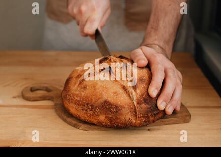 l'uomo affetta del pane fresco su un tavolo di legno Foto Stock
