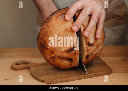 l'uomo affetta del pane fresco su un tavolo di legno Foto Stock