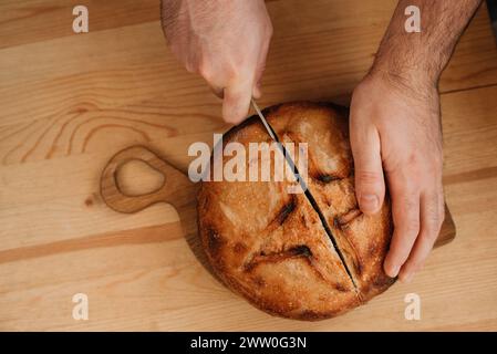 l'uomo affetta del pane fresco su un tavolo di legno Foto Stock