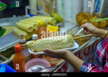 Donna messicana che prepara un mais bollito, tipico cibo di strada messicano. Stallo di cibo. Elote. Foto Stock