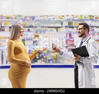 Medico che dà medicinali a una donna incinta all'interno di una farmacia Foto Stock