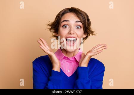 Foto di una donna funky impressionata indossa un pullover blu che urla sì sfondo di colore beige isolato Foto Stock