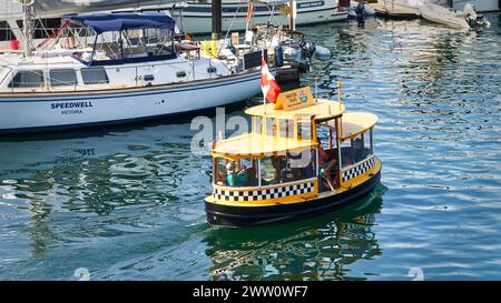 Un traghetto giallo luminoso del porto con persone che viaggiano sull'acqua dell'oceano a Victoria, British Columbia Foto Stock