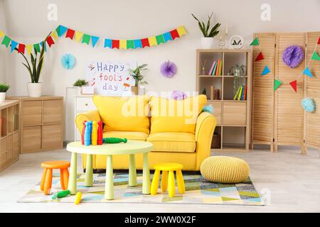 Interno del soggiorno decorato per il giorno del Fool di aprile con divano e giocoleria sul tavolo Foto Stock