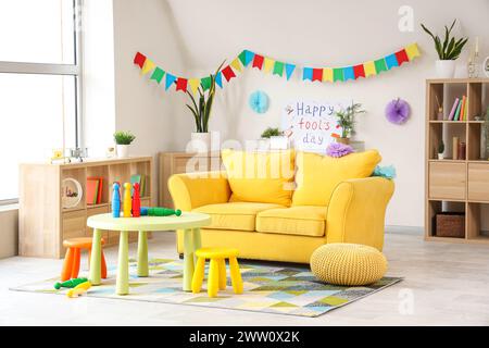 Interno del soggiorno decorato per il giorno del Fool di aprile con divano e giocoleria sul tavolo Foto Stock