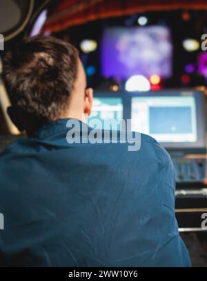 Vista dell'operatore del tecnico dell'illuminazione che lavora sul posto di lavoro della console di miscelazione durante un concerto di eventi dal vivo sul palco della trasmissione, il controllore del miscelatore di luce PAN Foto Stock