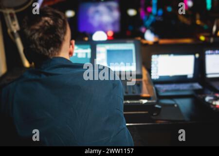 Vista dell'operatore del tecnico dell'illuminazione che lavora sul posto di lavoro della console di miscelazione durante un concerto di eventi dal vivo sul palco della trasmissione, il controllore del miscelatore di luce PAN Foto Stock