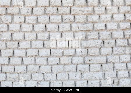 Struttura di fondo in mattoni di argilla grigia naturale fatta a mano con conchiglie incluse in un vecchio cottage costiero con agenti atmosferici Foto Stock