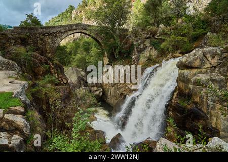 Vista dell'antico Ponte romano Mizarela, o Ponte del Diavolo con un bellissimo arco e una pittoresca cascata, presso il Parco Nazionale Peneda Geres a Portu Foto Stock