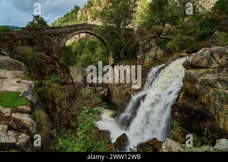 Vista dell'antico Ponte romano Mizarela, o Ponte del Diavolo con un bellissimo arco e una pittoresca cascata, presso il Parco Nazionale Peneda Geres a Portu Foto Stock