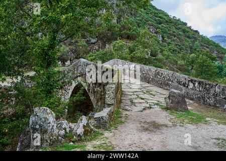 Vista dell'antico Ponte romano Mizarela, o Ponte del Diavolo con un bellissimo arco e una pittoresca cascata, presso il Parco Nazionale Peneda Geres a Portu Foto Stock