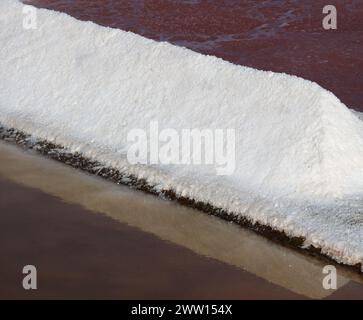 Portogallo, Algarve. Fleur de sel raccolto. Tumulo di sale e riflessi alla luce del sole del tardo pomeriggio. Foto Stock