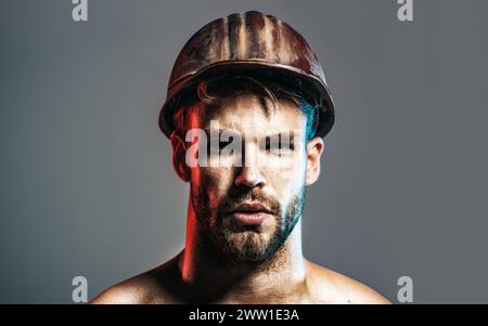 Primo piano ritratto costruttore serio con casco protettivo. Bell'ingegnere, architetto o lavoratore industriale maschile in elmetto di sicurezza. Forte barba Foto Stock