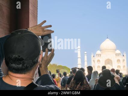 I turisti scattano foto con il telefono al Taj Mahal dall'ingresso principale di Agra Foto Stock