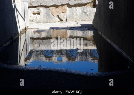 Riflesso dei portici interni dell'anfiteatro Arles in una pozzanghera - Arènes d'Arles - un anfiteatro romano ad Arles in Francia Foto Stock