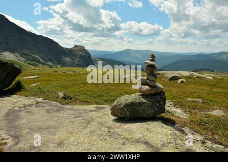 Una piramide di pietra sulla cima di una grande pietra piatta in una pittoresca valle circondata da alte montagne. Parco naturale Ergaki, regione di Krasnoyarsk, Sib Foto Stock