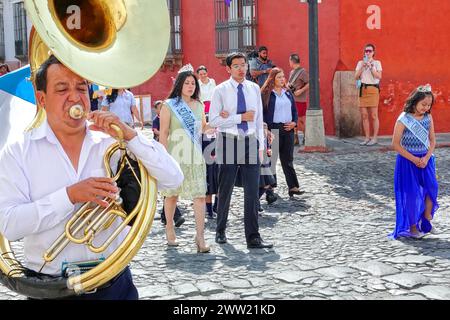 Antigua, Guatemala. 20 marzo 2024. Una banda di marcia conduce la Semana Santa Festival Queen, circondata da bambini delle scuole, mentre sfilava attraverso il centro storico in preparazione della settimana Holly, 20 marzo 2024 ad Antigua, Guatemala. Le sontuose processioni, le dettagliate alfombre e le tradizioni secolari attraggono oltre 1 milione di persone nell'antica capitale. Crediti: Richard Ellis/Richard Ellis/Alamy Live News Foto Stock