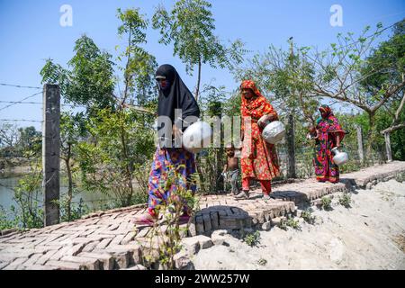 10 marzo 2024, Dacca, Bangladesh: La gente va in uno stagno per raccogliere acqua potabile a Shyamnagar Gabura nel distretto di Satkhira. Nel Gabura Union, distretto di Shatkhira, nel Bangladesh meridionale, i residenti stanno affrontando una terribile crisi di acqua potabile esacerbata dai cambiamenti climatici. Le persone, comprese donne e bambini, devono percorrere quotidianamente lunghe distanze per accedere a fonti di acqua sicure, aumentando i rischi per la salute derivanti dalle malattie trasmesse dall'acqua. I dati a livello di distretto costiero evidenziano percentuali significative che si trovano a fronteggiare la carenza di acqua, mentre gli ambientalisti suggeriscono che la situazione è più grave. In diminuzione di undergr Foto Stock