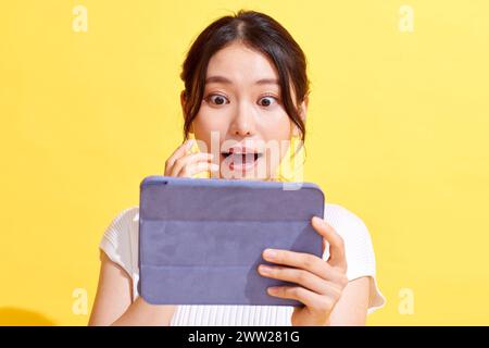 Una donna che tiene un tablet con uno sguardo sorpreso sul viso Foto Stock