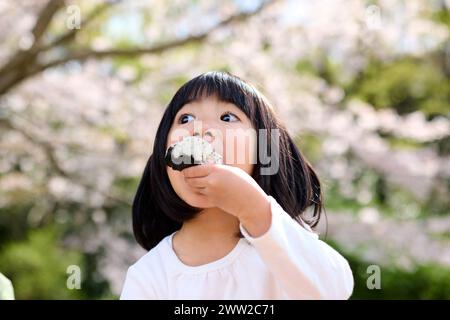 Una bambina che mangia una palla di riso Foto Stock