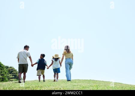 Una famiglia che cammina su una collina erbosa Foto Stock