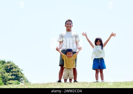 Un uomo e due bambini in cima a una collina erbosa Foto Stock