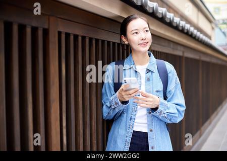 Una donna con una giacca in denim che tiene un cellulare Foto Stock